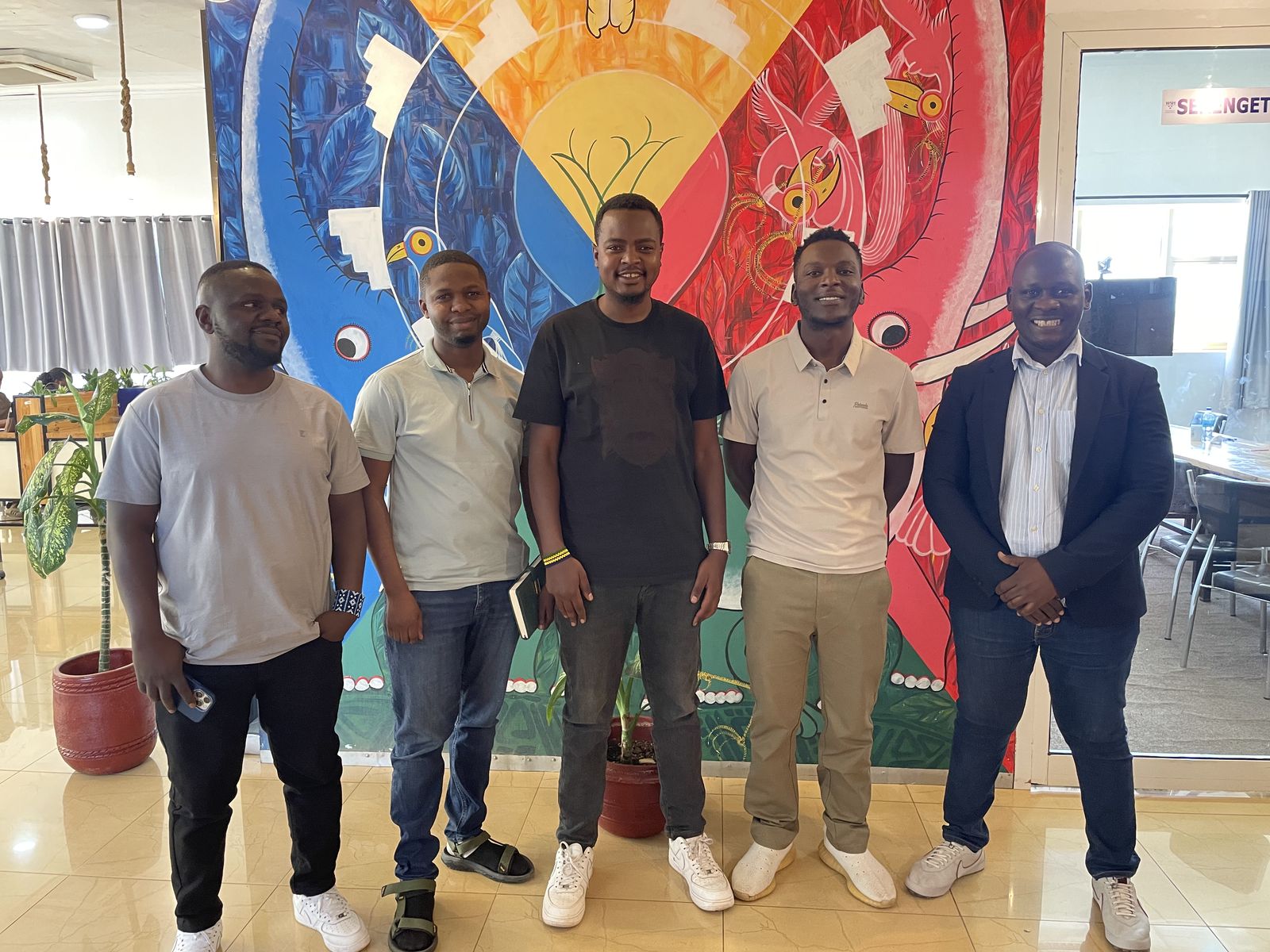 Five participants standing in front of a colourful mural